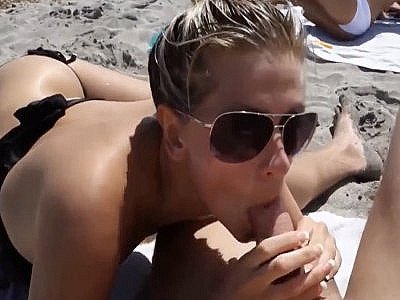 Une belle blonde suce un mec sur une plage