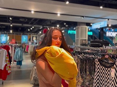 Une jolie brune avec des obus essaye un pull dans un magasin