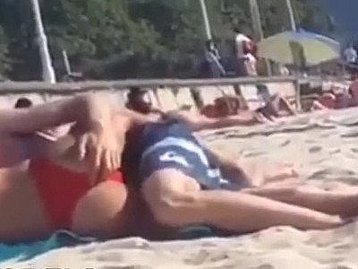 Un couple baise discrètement sur une plage blindée de monde